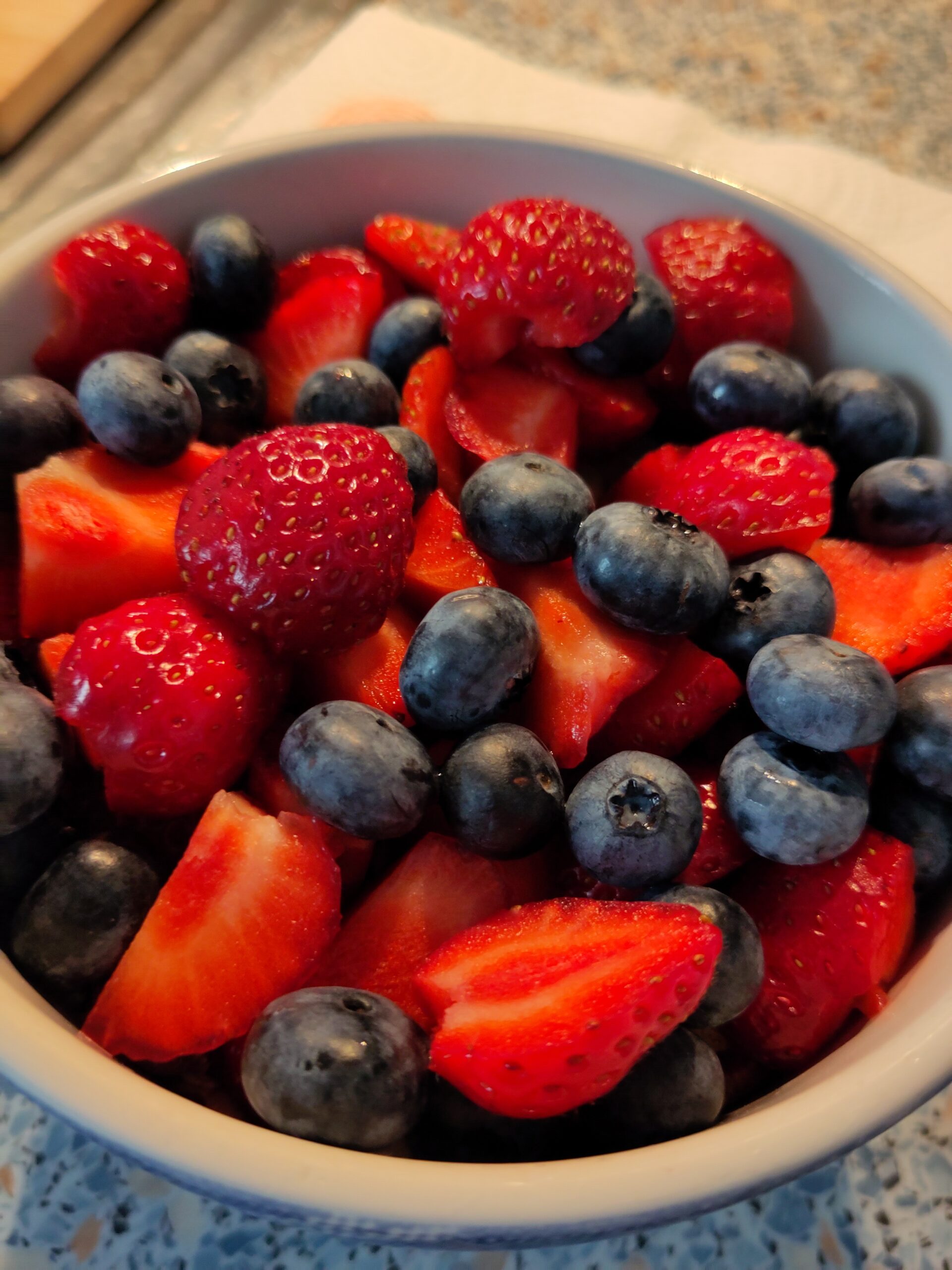 Eine Müslischale mit Früchten darin: Heidelbeeren, Erdbeeren liegen oben.
