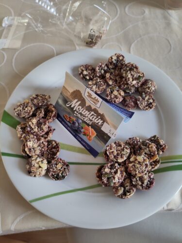 Runder Teller auf einem Tisch. Halbkugelrömige Kekse liegen in drei Haufen verteilt. In der Mitte ein Schild mit nährerer Bezeichnung der Kekse.