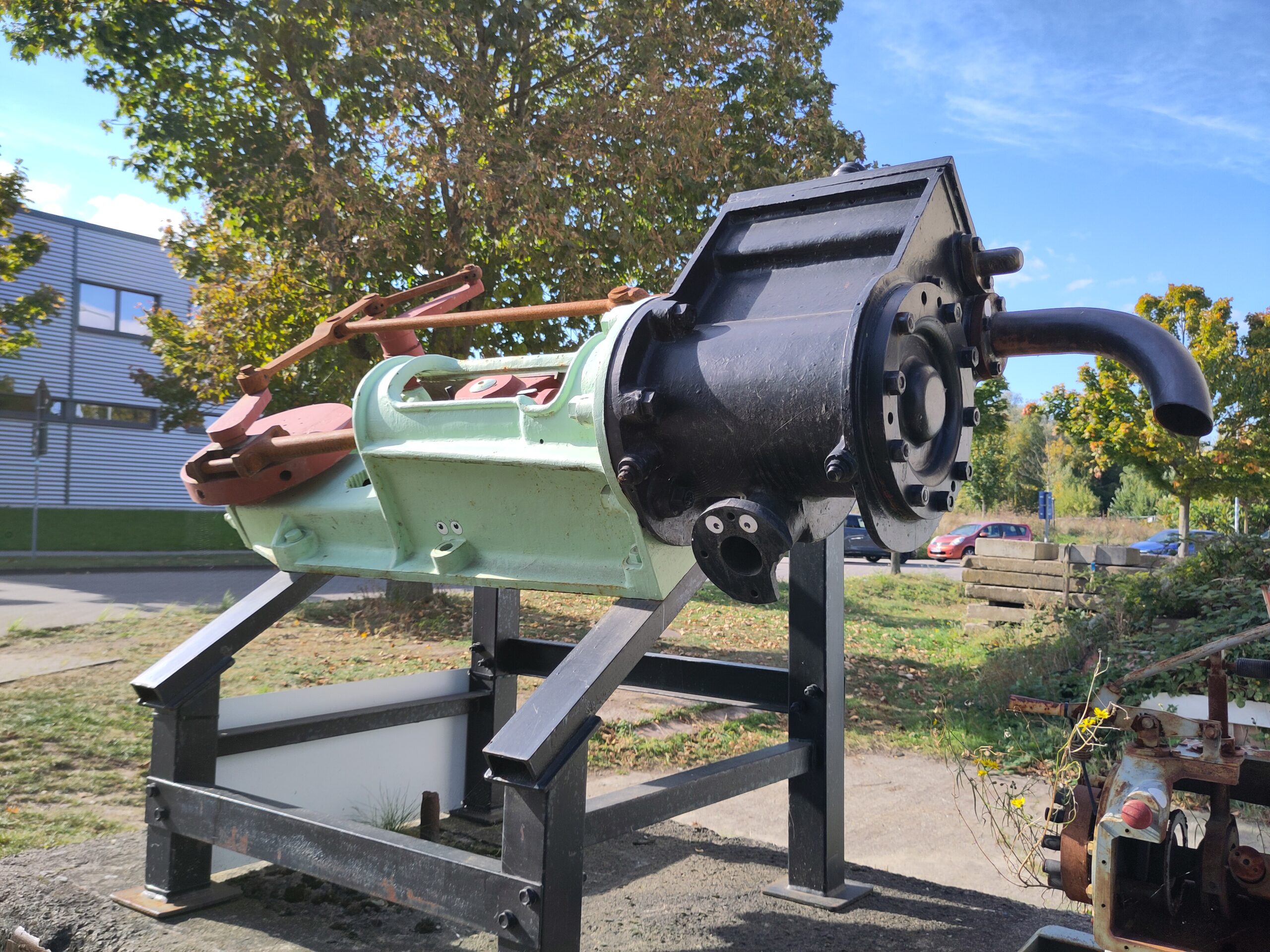 Ein alter Kolben mit angewickeltem Austrittsrohr auf einem Gestell.